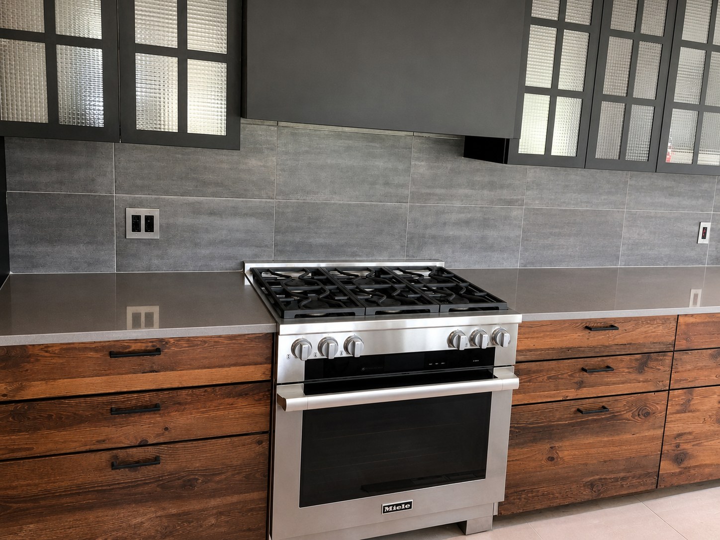 Modern kitchen renovation with reclaimed wood cabinetry, professional gas range, and gray stone tile backsplash — New York City